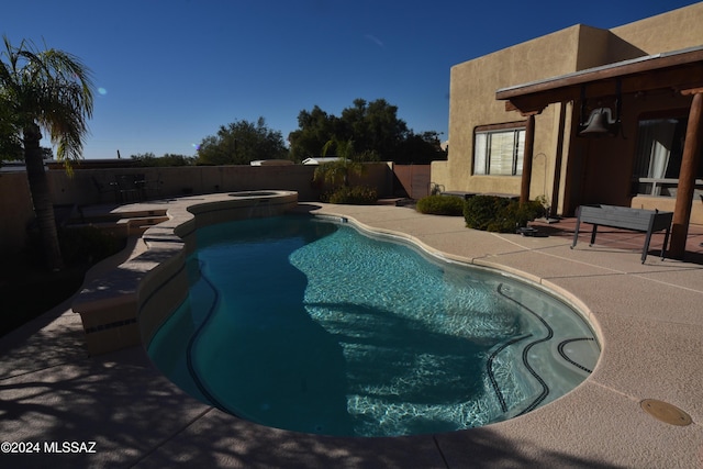 view of swimming pool with a fenced backyard, a pool with connected hot tub, and a patio area