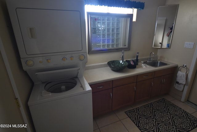 laundry room featuring sink, light tile patterned flooring, and stacked washing maching and dryer