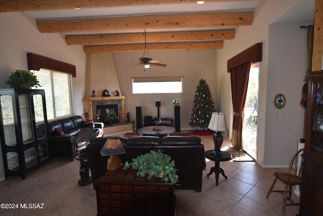 living room with beamed ceiling, light tile patterned floors, a large fireplace, and ceiling fan