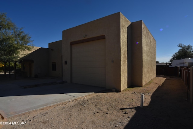 view of home's exterior featuring stucco siding, an attached garage, fence, and concrete driveway
