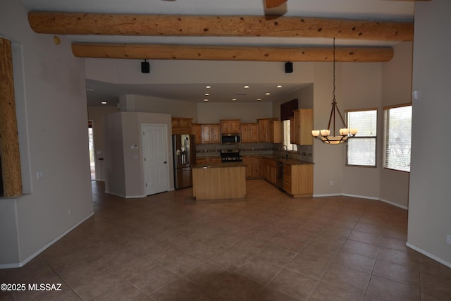 kitchen with a sink, appliances with stainless steel finishes, beamed ceiling, and baseboards