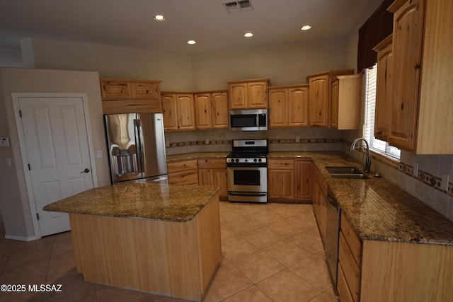 kitchen featuring dark stone counters, a sink, stainless steel appliances, and light tile patterned floors
