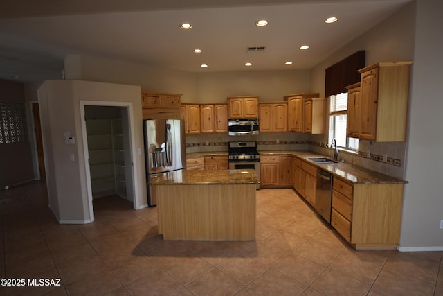 kitchen featuring appliances with stainless steel finishes, sink, a kitchen island, and dark stone countertops