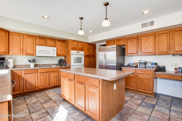 kitchen with a center island, pendant lighting, and white appliances