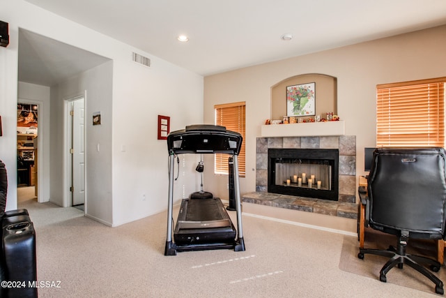 exercise room featuring carpet flooring and a tile fireplace