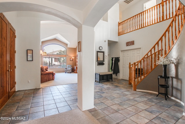 foyer entrance with carpet and high vaulted ceiling