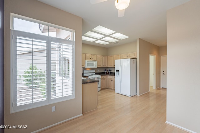 kitchen with light hardwood / wood-style floors, white appliances, and a skylight