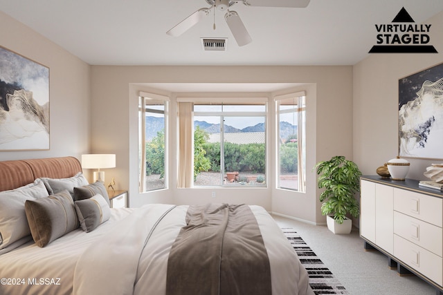 bedroom with a mountain view, carpet flooring, and ceiling fan