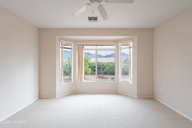 unfurnished room featuring a wealth of natural light, a mountain view, and light carpet