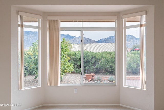 carpeted empty room featuring a mountain view and plenty of natural light