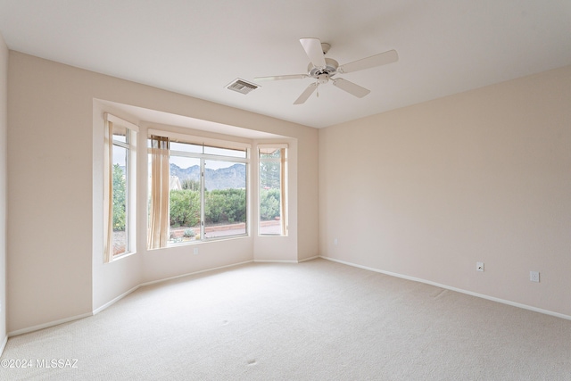 carpeted empty room featuring a mountain view and ceiling fan