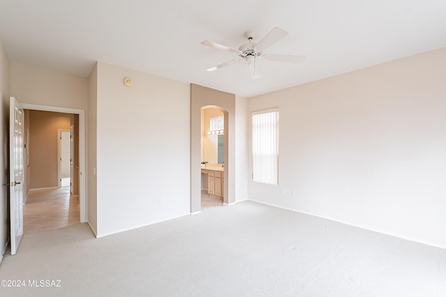 unfurnished bedroom featuring ceiling fan, light colored carpet, and connected bathroom