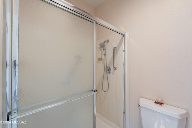 bathroom featuring toilet and an enclosed shower