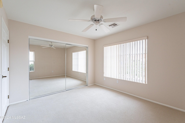 unfurnished bedroom featuring ceiling fan, light carpet, and a closet