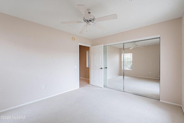 unfurnished bedroom with light colored carpet, a closet, and ceiling fan