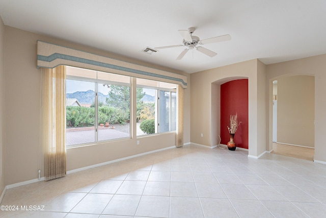 spare room featuring a mountain view, light tile patterned floors, and ceiling fan