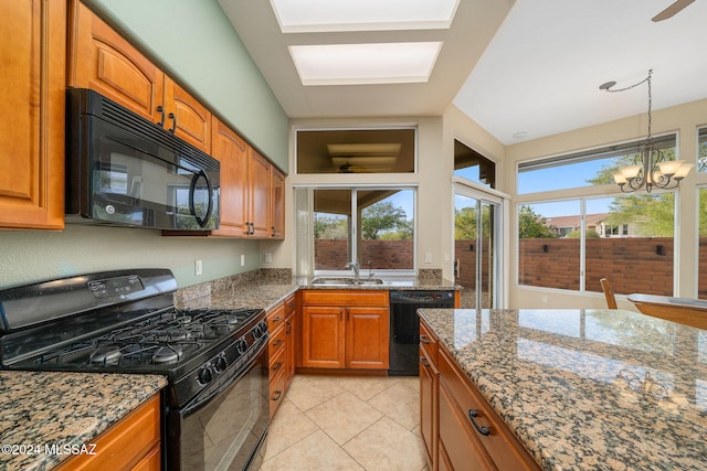 kitchen with an inviting chandelier, black appliances, sink, stone countertops, and light tile patterned flooring