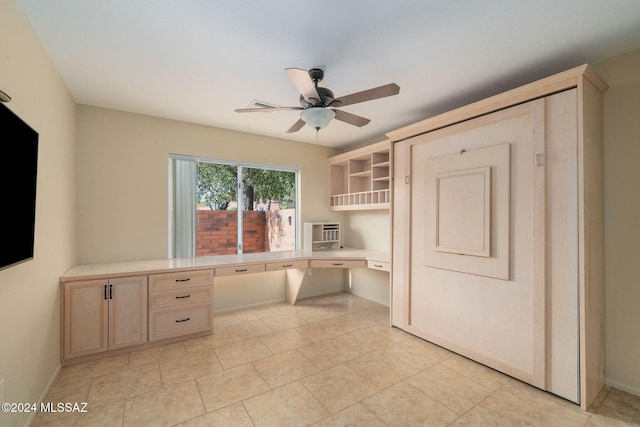 unfurnished office with light tile patterned floors, built in desk, a wall unit AC, and ceiling fan