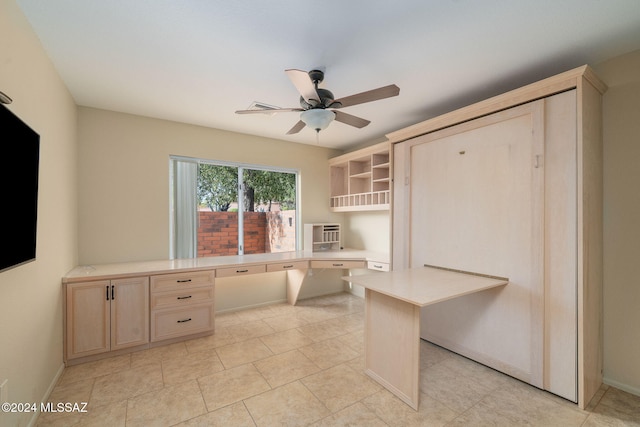 unfurnished office with light tile patterned floors, built in desk, an AC wall unit, and ceiling fan