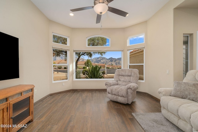 interior space with a mountain view, ceiling fan, a towering ceiling, and dark wood-type flooring