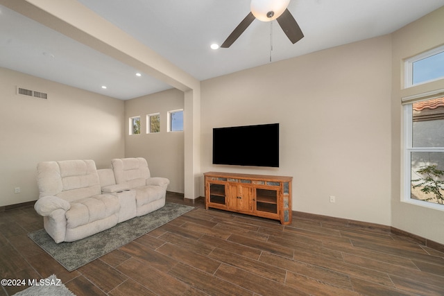 living room featuring beam ceiling, ceiling fan, and dark wood-type flooring