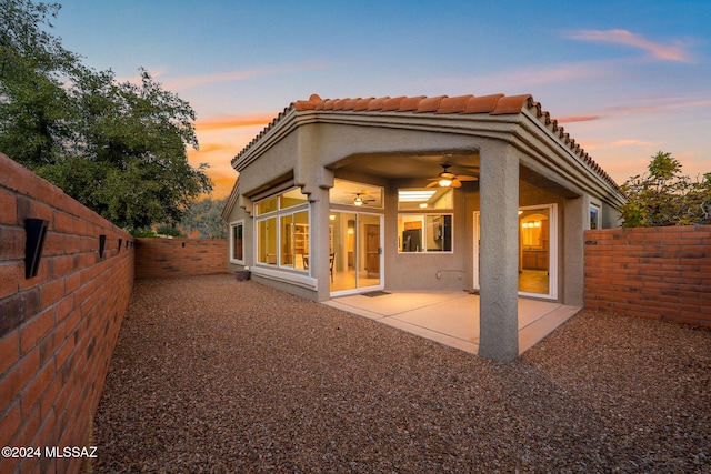 back house at dusk with a patio area and ceiling fan