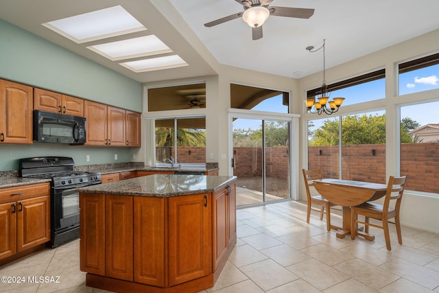 kitchen with a center island, dark stone countertops, pendant lighting, light tile patterned floors, and black appliances