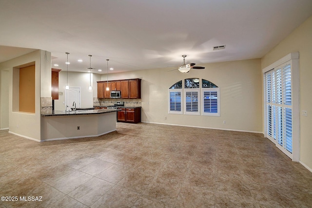 kitchen with kitchen peninsula, appliances with stainless steel finishes, tasteful backsplash, pendant lighting, and sink