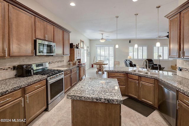 kitchen with sink, pendant lighting, stainless steel appliances, and a kitchen island