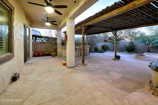 view of patio / terrace with ceiling fan, a bar, and a fire pit