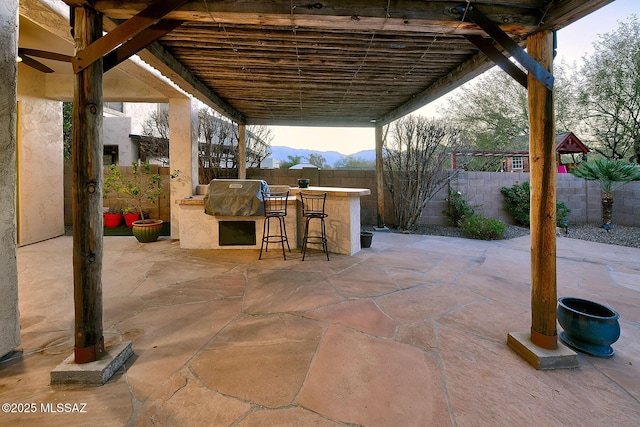 view of patio / terrace featuring a mountain view, a bar, and area for grilling