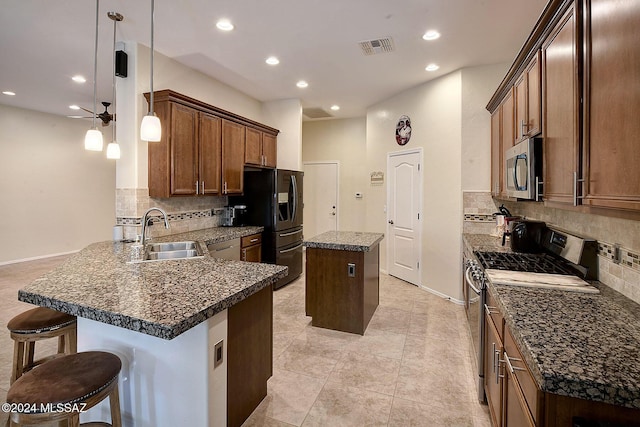 kitchen featuring stainless steel appliances, backsplash, a center island, hanging light fixtures, and sink