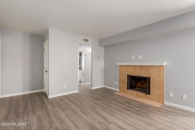 unfurnished living room featuring a tile fireplace and hardwood / wood-style flooring