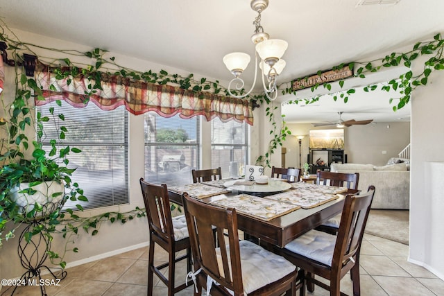 dining area with light tile patterned flooring and ceiling fan with notable chandelier