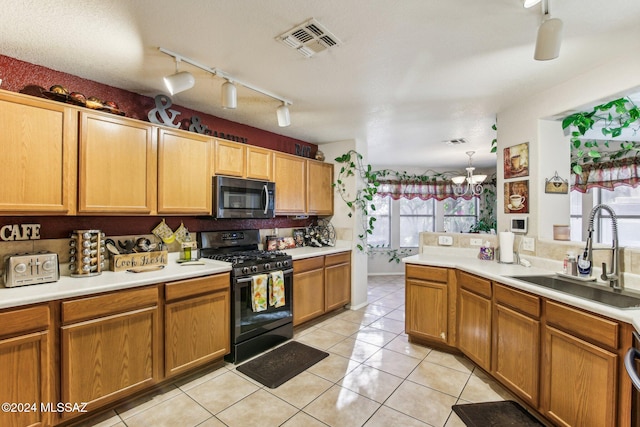 kitchen featuring a chandelier, black gas range, a healthy amount of sunlight, and sink