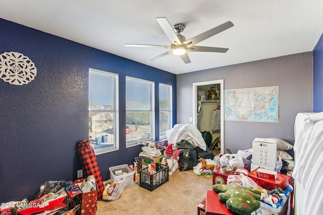 rec room with carpet, a textured ceiling, and ceiling fan