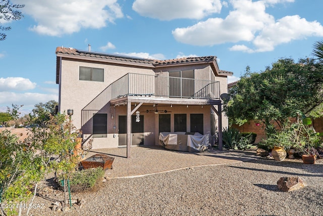 rear view of house featuring a balcony, a garage, and solar panels