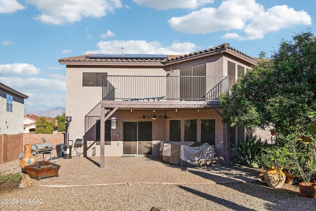 back of property featuring solar panels, a balcony, and a patio area