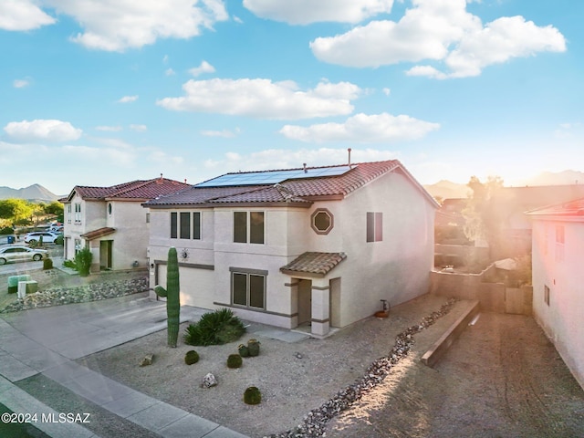 view of front of property with a mountain view and solar panels