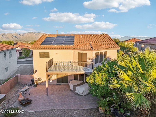 rear view of house with a patio area, a mountain view, and solar panels