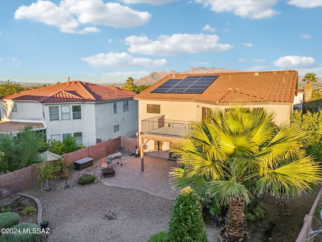 back of property featuring a patio area, a balcony, and solar panels