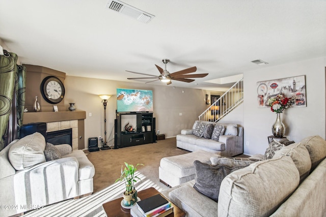 living room featuring carpet flooring, ceiling fan, and a tiled fireplace