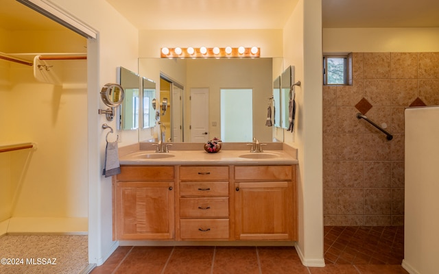 bathroom with tile patterned flooring, vanity, and a tile shower