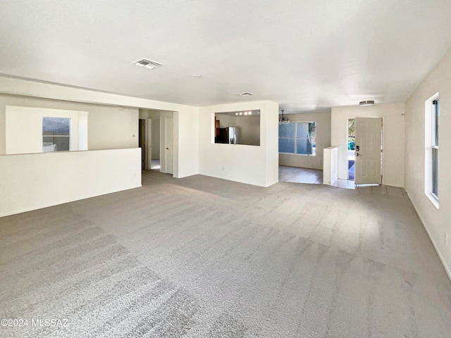 unfurnished living room featuring carpet flooring and plenty of natural light