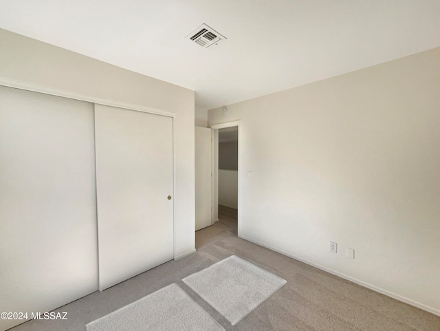 unfurnished bedroom with light carpet and a closet