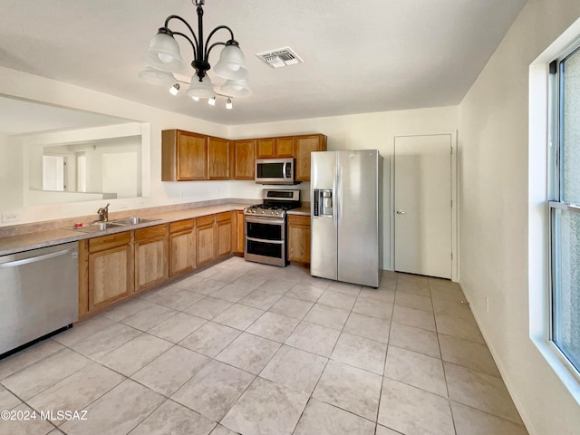 kitchen featuring appliances with stainless steel finishes, sink, light tile patterned floors, a notable chandelier, and hanging light fixtures