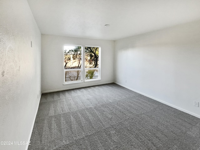 unfurnished room with dark colored carpet