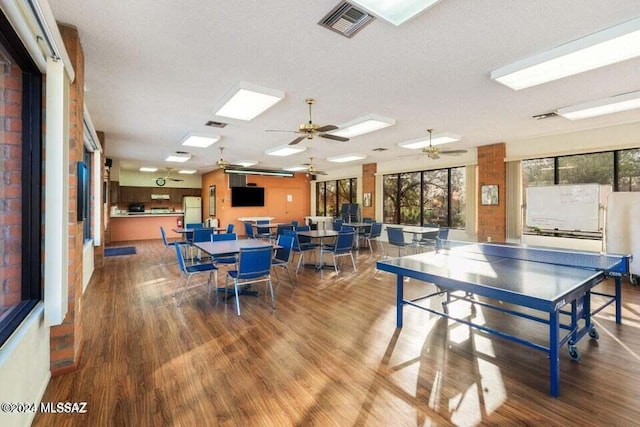 game room featuring hardwood / wood-style floors, ceiling fan, and a textured ceiling