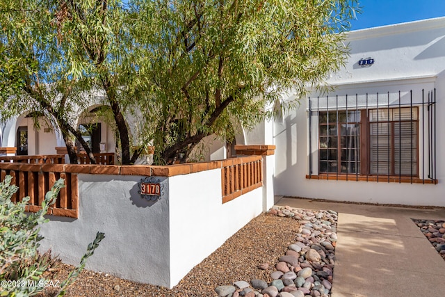 view of side of property with a fenced front yard and stucco siding