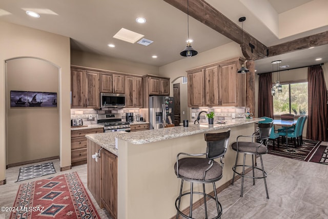 kitchen featuring light stone countertops, a breakfast bar, hanging light fixtures, and appliances with stainless steel finishes